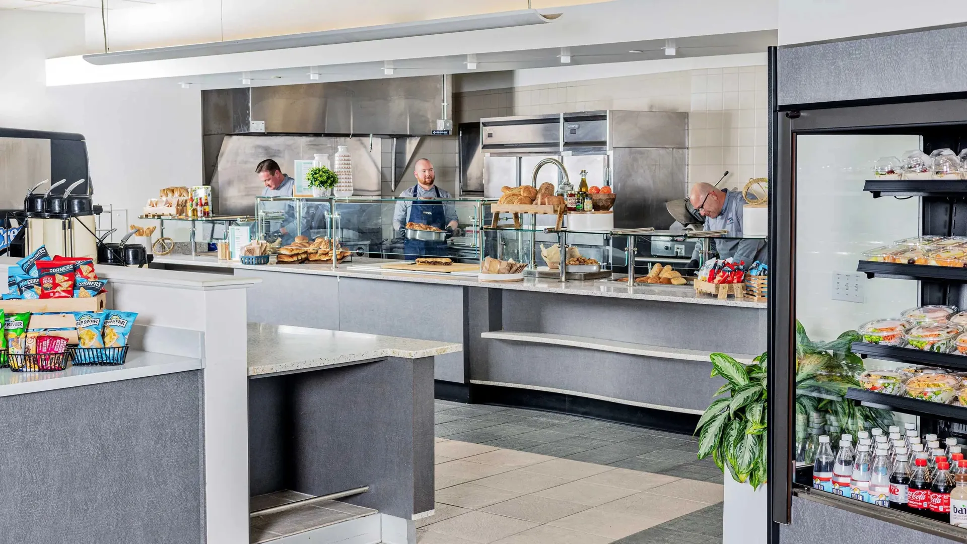 Wide shot of corporate cafeteria, with two chefs in the background working behind the counter.