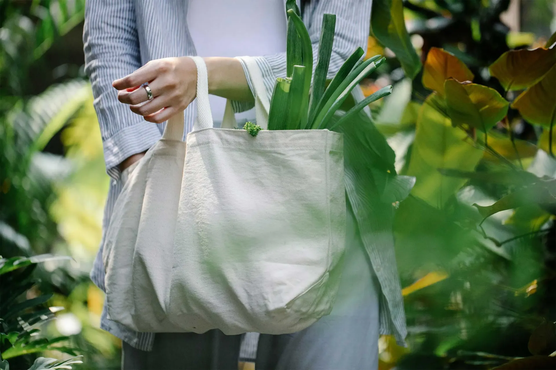 Hand holding canvas bag while shopping for produce