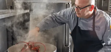 Chef David using tongs to pick up steamed lobster from pot